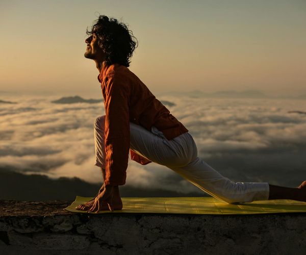 Silhouette of a person in a yoga warrior pose during sunrise.